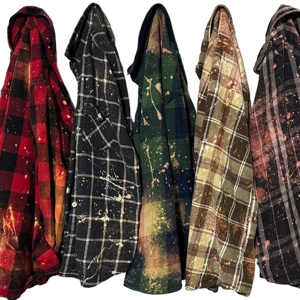 Row of custom bleach-splatter flannel shirts on hangers.